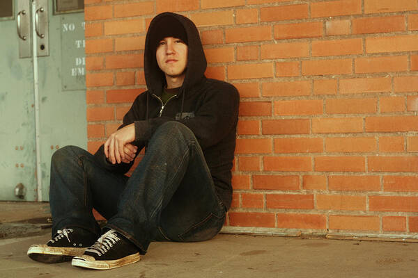 Confusion Art Print featuring the photograph Punk and a hoodie with dirty shoes sitting by brick wall by Jordanchez