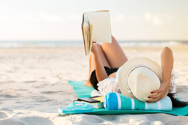 Mid Adult Women Art Print featuring the photograph Woman lies on the beach reading a book by Steve Debenport