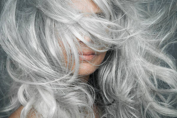 Mature Adult Art Print featuring the photograph Woman with grey hair blowing across her face. by Andreas Kuehn