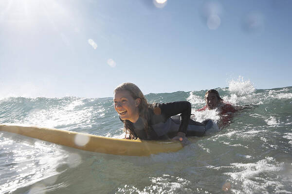 Three Quarter Length Art Print featuring the photograph Young man being towed in sea by young woman on surfboard, smiling by Anthony Ong