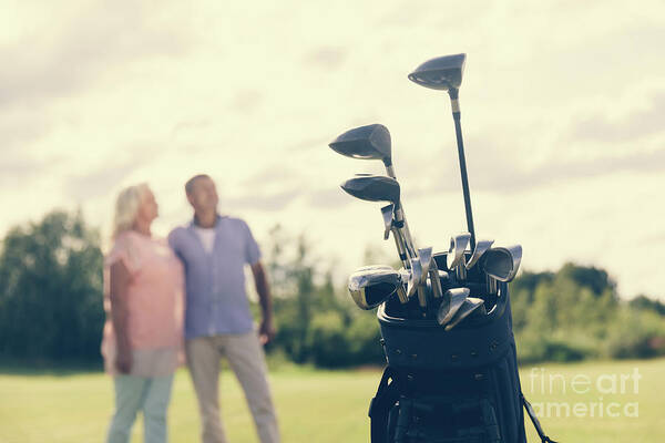 Golf Art Print featuring the photograph Golf bag standing on a grass field, people in the background by Michal Bednarek