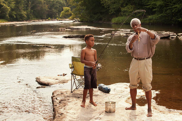Boy Holding Fishing Rod By Grandfather Looking At Fish At Lake Art Print