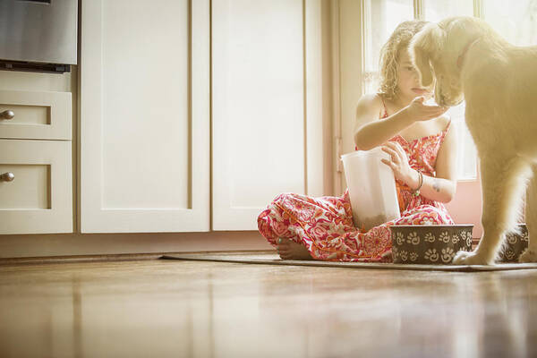 Pets Art Print featuring the photograph Caucasian girl sitting on kitchen floor feeding dog #3 by Terry Vine