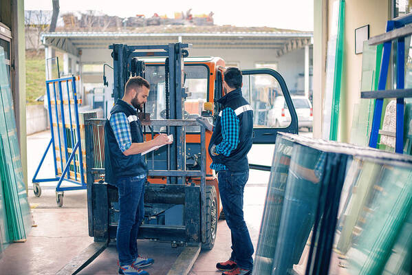 Clipboard Art Print featuring the photograph Workers in warehouse with forklift #5 by Bluecinema