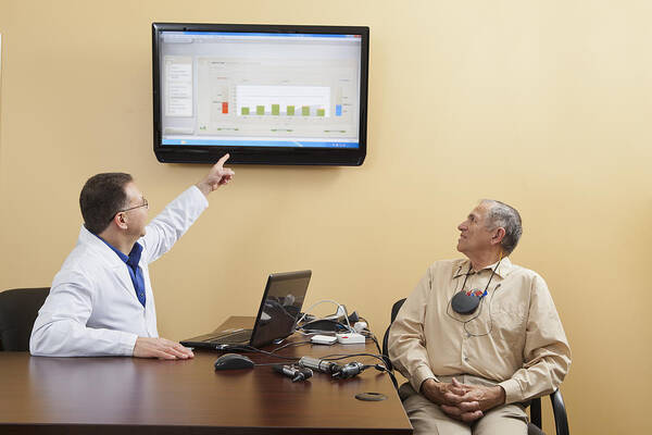 Expertise Art Print featuring the photograph Audiologist explaining diagrams for a patient wearing hearing device programmer by Huntstock