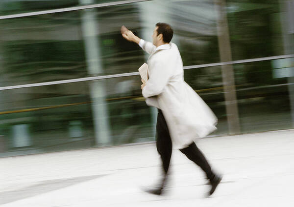 Working Art Print featuring the photograph Businessman walking in street, hand raised, blurred by Eric Audras