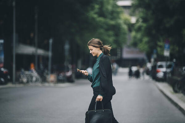 Internet Art Print featuring the photograph Confident businesswoman using smart phone while crossing street in city by Maskot