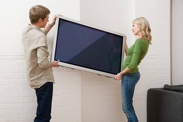 Young Men Art Print featuring the photograph Couple carrying plasma screen television by Image Source