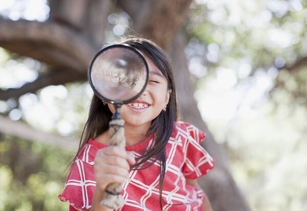 Asian And Indian Ethnicities Art Print featuring the photograph Girl using magnifying glass outdoors by Paul Bradbury
