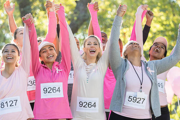 Human Arm Art Print featuring the photograph Happy breast cancer survivors hold hands and cheer by SDI Productions