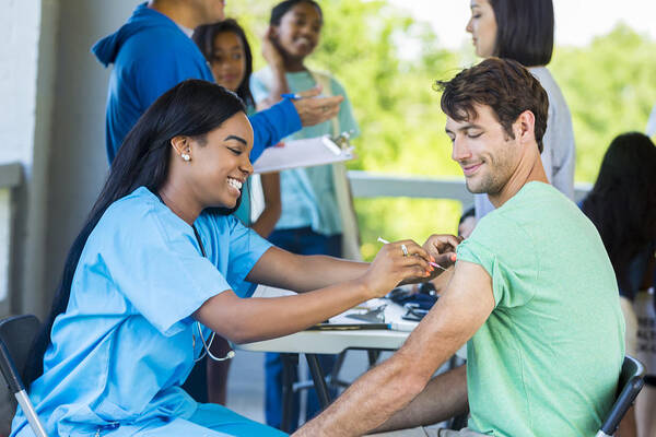 People Art Print featuring the photograph Man receives immunization at outdoor free clinic by SDI Productions