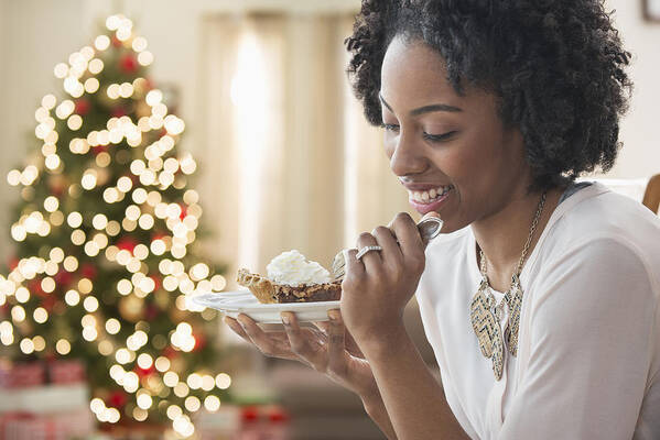 People Art Print featuring the photograph Mixed race woman eating dessert by Christmas tree by Jose Luis Pelaez Inc