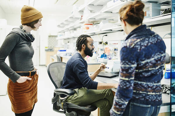 Expertise Art Print featuring the photograph Scientist discussing data with colleagues while working in research lab by Thomas Barwick