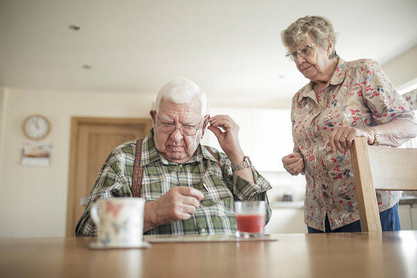 Breakfast Art Print featuring the photograph Senior Man Inserting His Hearing Aid by SolStock