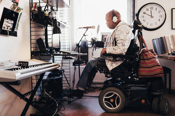 Working Art Print featuring the photograph Side view of disabled musician with headphones in recording studio by Maskot