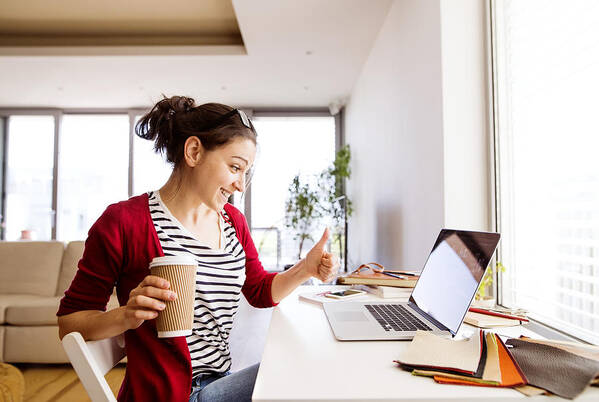 Working Art Print featuring the photograph Smiling woman with coffee to go at desk at home by Westend61