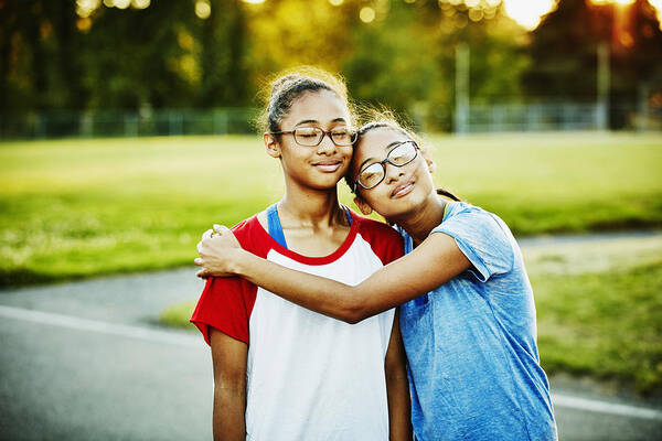 Outdoors Art Print featuring the photograph Twin sisters embracing on basketball court by Thomas Barwick