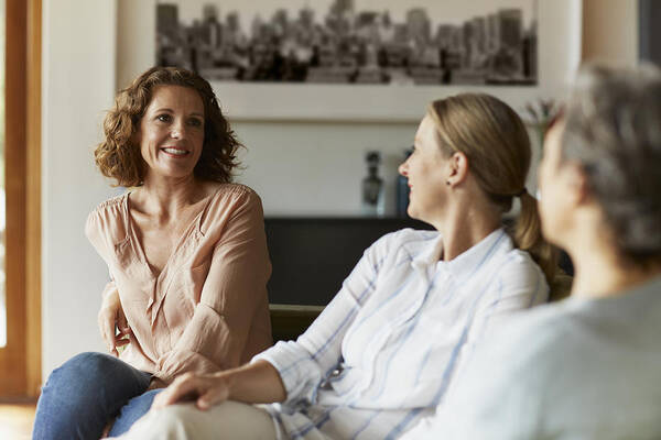 Three Quarter Length Art Print featuring the photograph Woman conversing with friends at home by Morsa Images