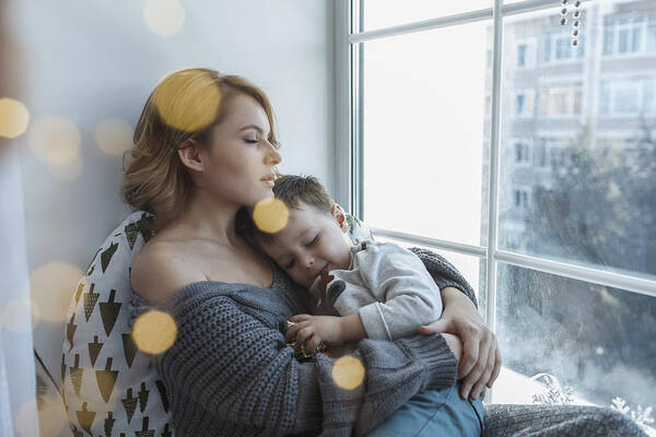 Home Interior Art Print featuring the photograph Young woman relaxing with son by window at home by Vasily Pindyurin