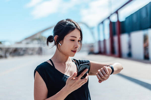 Internet Art Print featuring the photograph Young woman using smartwatch and doing outdoor workout in the city by Oscar Wong