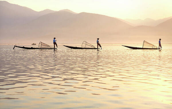 Intha 'leg Rowing' Fishermen At Sunset On Inle Lakeswho Row Traditional Wooden Boats Using Their Leg And Fish Using Nets Stretched Over Conical Bamboo Frames Art Print featuring the photograph 321-5139 by Robert Harding Picture Library