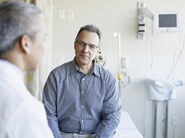 Mature Adult Art Print featuring the photograph Doctor talking to patient in hospital room by Thomas Barwick