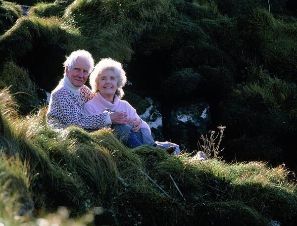 Elderly Couple Art Print featuring the photograph Elderly Couple On A Grassy Slope In Countryside by Ron Sutherland/science Photo Library