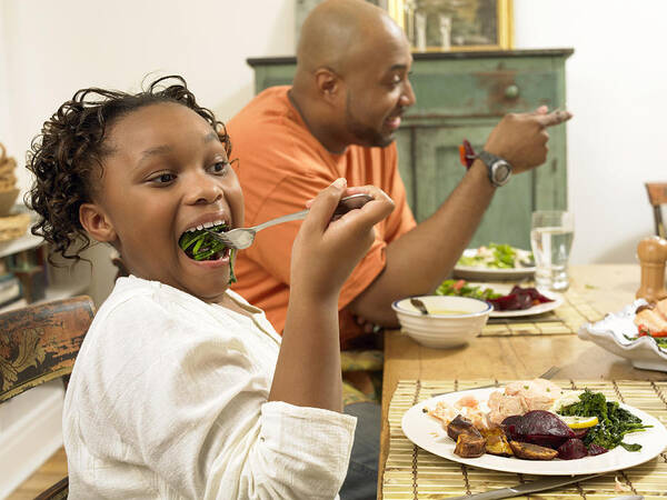 Part Of A Series Art Print featuring the photograph Young Girl Sits at a Table With Her Father, Eating Vegetables on a Fork by Digital Vision.