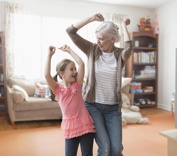 Human Arm Art Print featuring the photograph Caucasian grandmother and granddaughter dancing in living room by Jose Luis Pelaez Inc