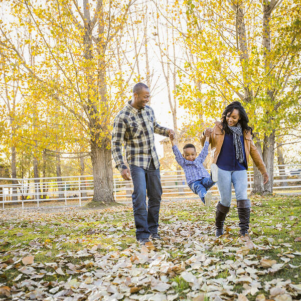 Hanging Art Print featuring the photograph Black family playing in autumn leaves by Mike Kemp