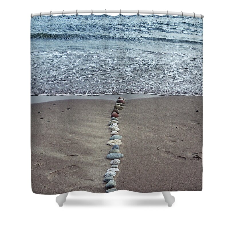 Water's Edge Shower Curtain featuring the photograph A Line Of Pebbles Arranged On The by Fiona Crawford Watson