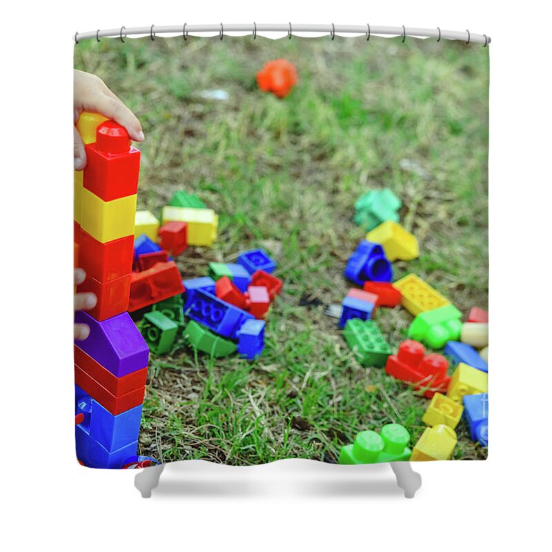 Activity Shower Curtain featuring the photograph Child playing with colorful blocks sitting on the ground of a garden in spring, negative space. by Joaquin Corbalan