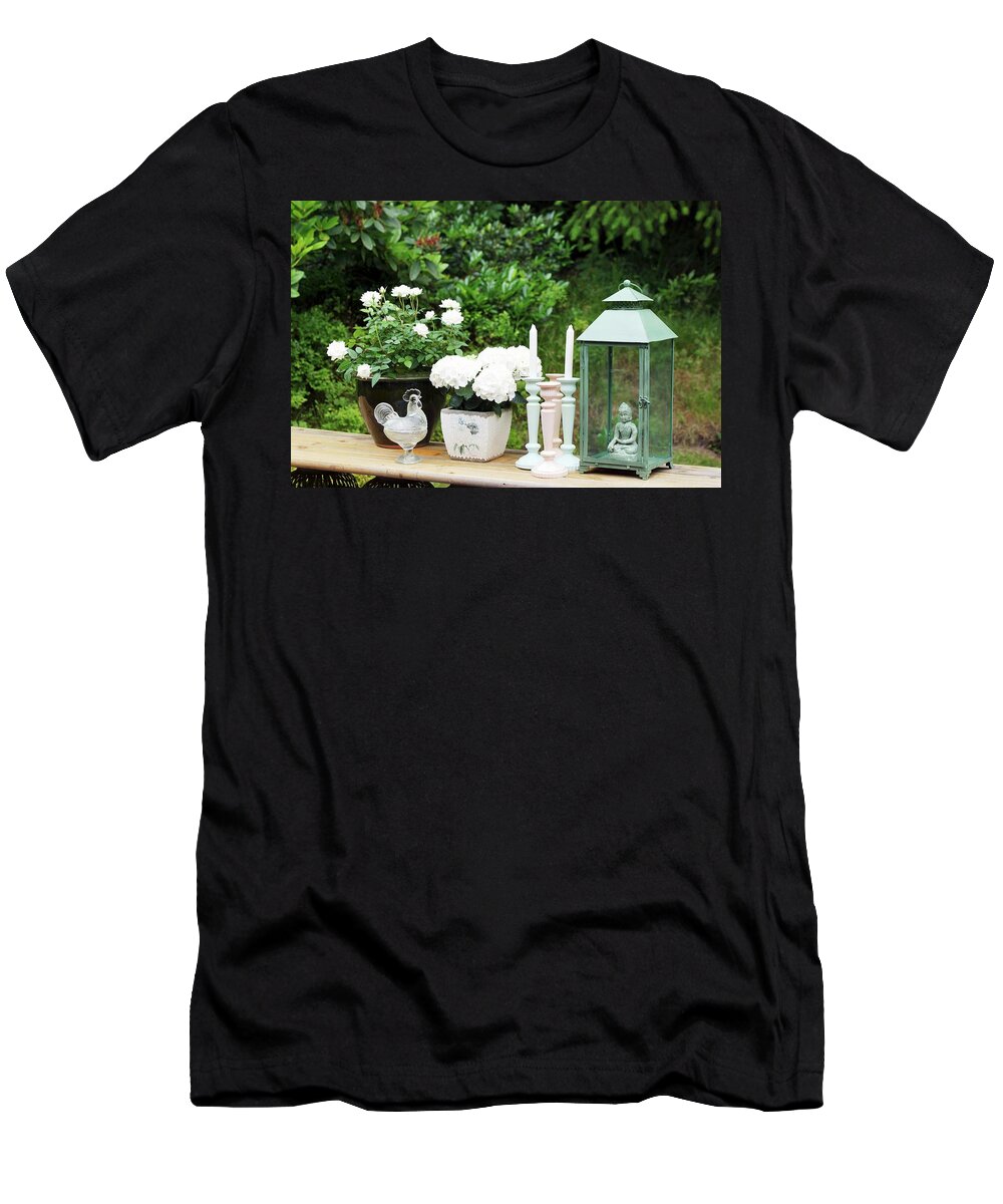 Ip_11221172 T-Shirt featuring the photograph Still-life In Garden; White Flowering Potted Plants And Candlesticks Next To Lantern On Simple Wooden Bench by Angelica Linnhoff