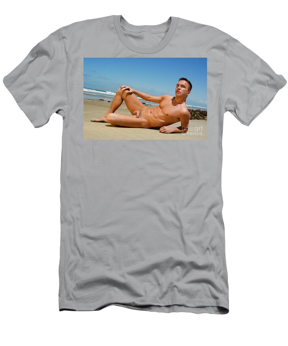 Nude T-Shirt featuring the photograph Handsome nude and muscular man poses on the wet sand at the beach. by Gunther Allen