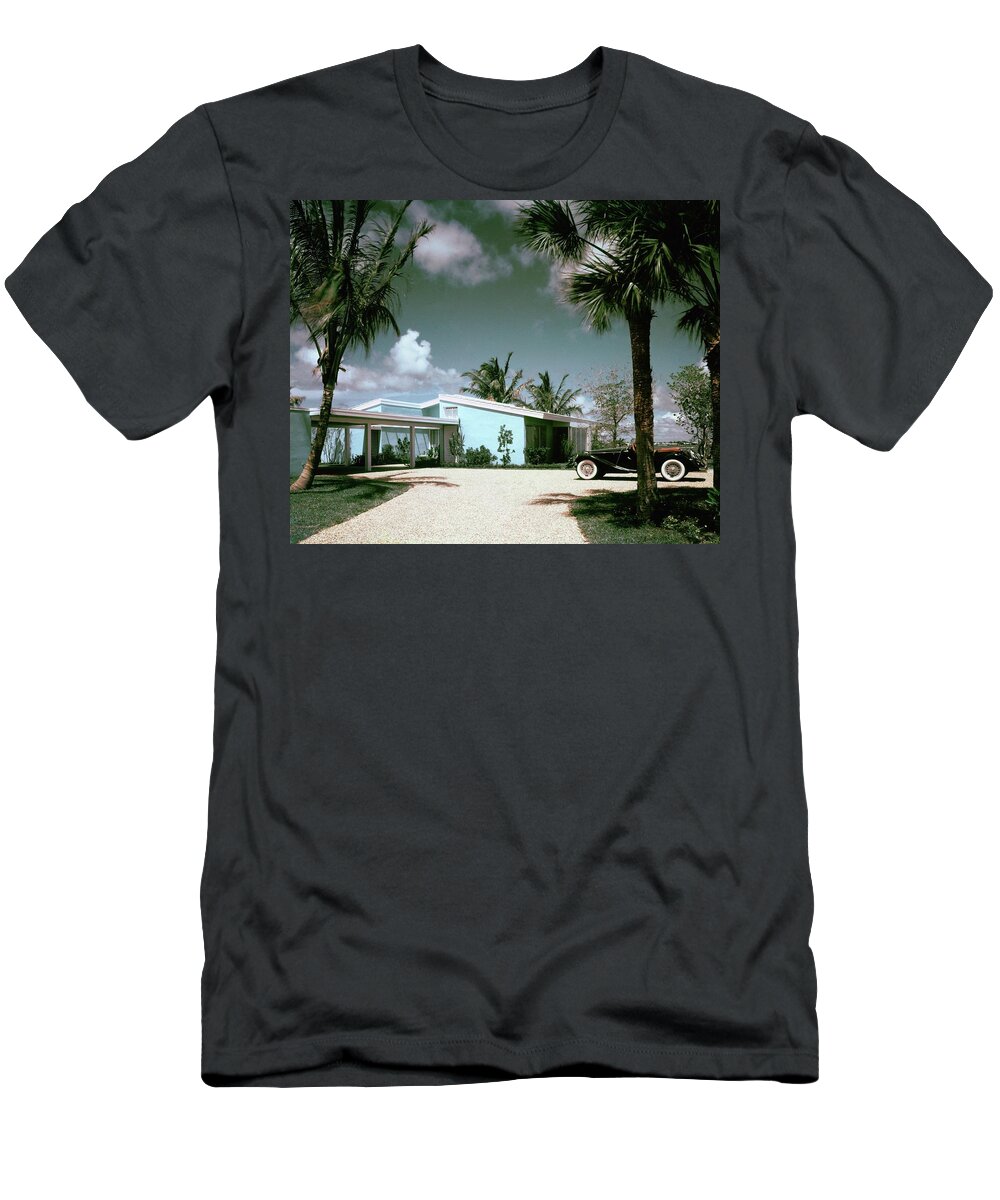 Nobodyoutdoorsdaytimehousedwellingdrivewayretroold-fashionedvintagevintage Cartransportationcarmotor Vehicleautomobilevehicletreemiamimiami-dade Countyfloridausanorth Americasouthern United Statesnorth American Atlantic Coastrobert M. Littlearchitecture #condenasthouse&gardenphotograph November 1st 1955 T-Shirt featuring the photograph A Vintage Car Parked Outside A Blue House by Tom Leonard