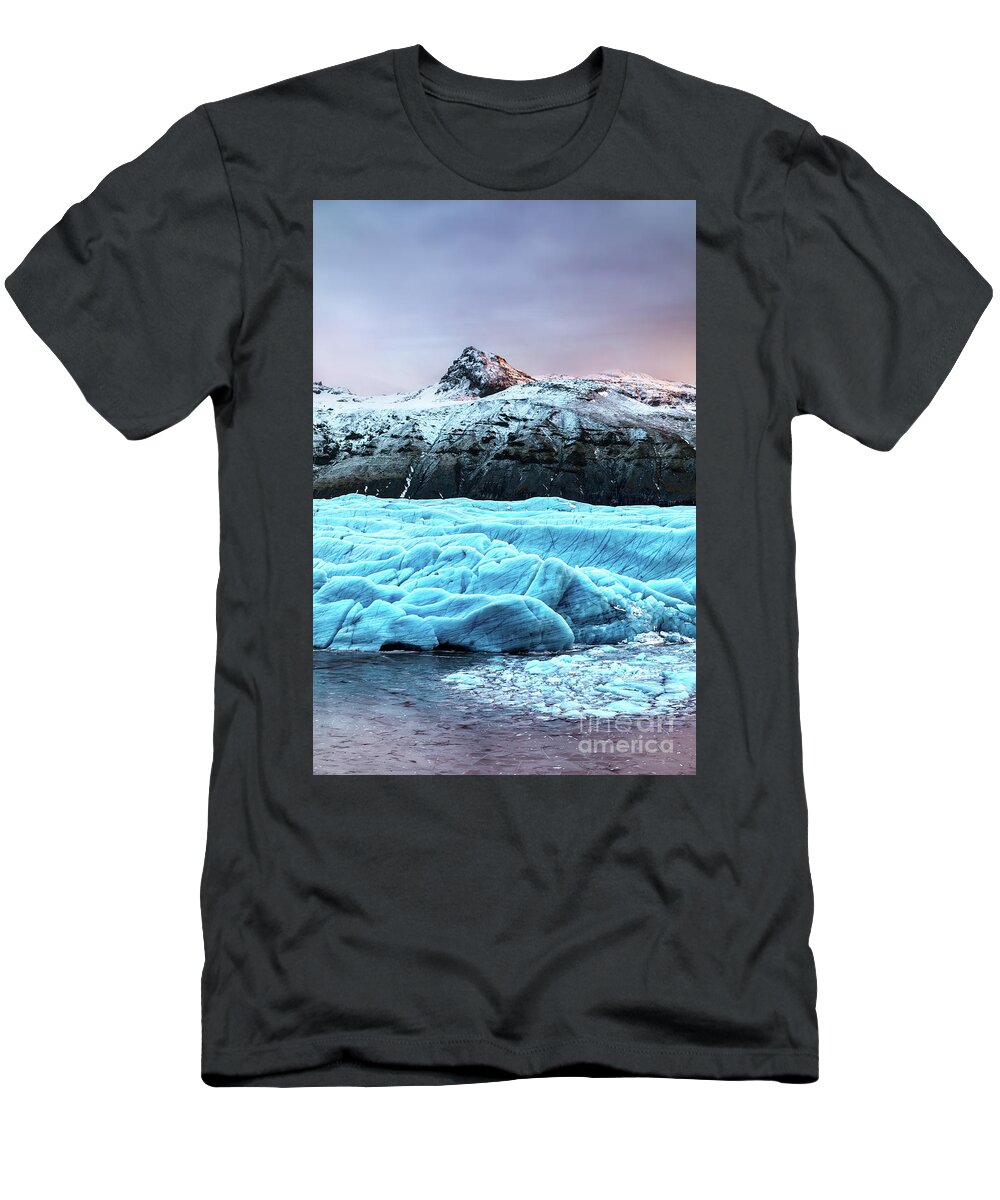 Arctic T-Shirt featuring the photograph Snow covered mountain and blue glacial ice of the Svinafellsjokul glacier in southeast Iceland. This is the largest ice cap in Europe. Winter scene at dusk. by Jane Rix