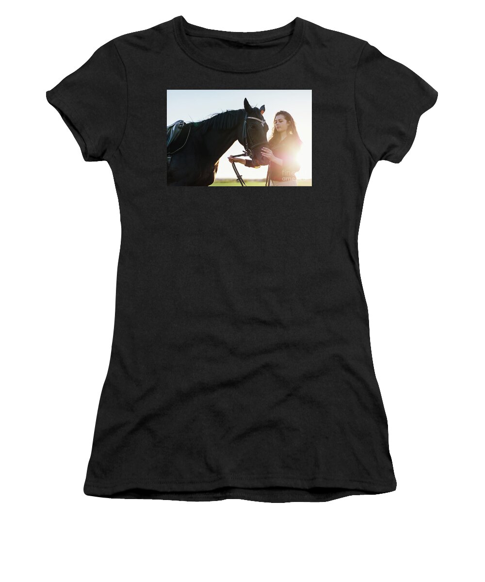Woman Women's T-Shirt featuring the photograph Attractive young woman holding a dark horse on a harness. by Michal Bednarek