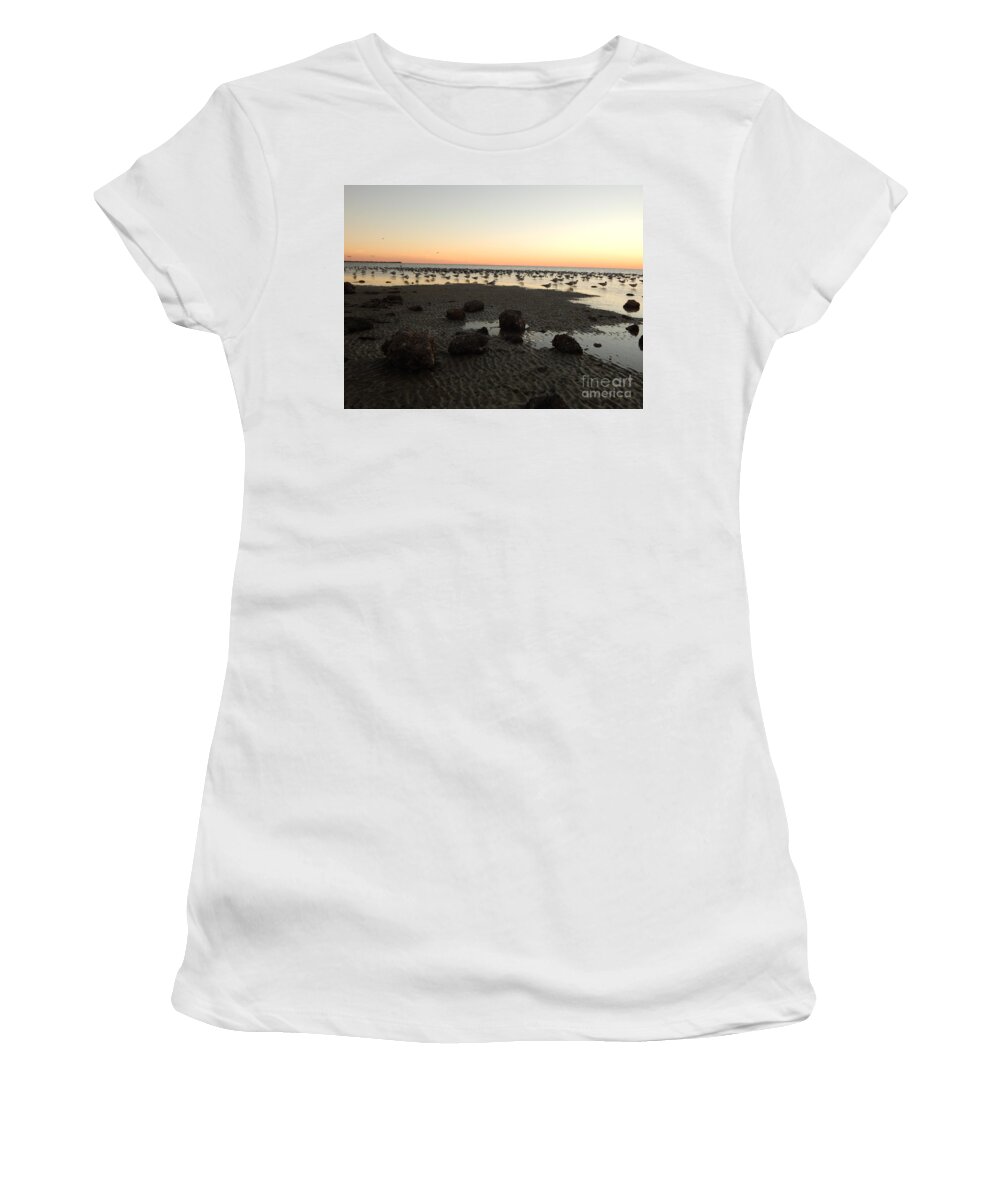 After Sunset Sky Glows Pale Orange At The Horizon As The Fading Light In The Sky Reflects In The Low Tide.sea Birds All Seem To Stare In The Same Direction Standing In The Shallows. Women's T-Shirt featuring the photograph Beach rocks barnacles and birds by Priscilla Batzell Expressionist Art Studio Gallery