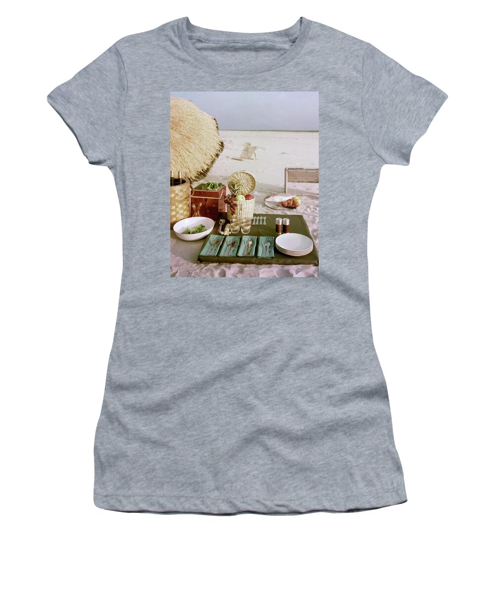 Leacockfrasertexaswarenobodystill Lifebeachsandseabasketfruitfoodlunchmealspoontablewarecutleryplateglassrecreationpicnic #condenasthouse&gardenphotograph June 1st 1954 Women's T-Shirt featuring the photograph A Beach Picnic by Wiliam Grigsby
