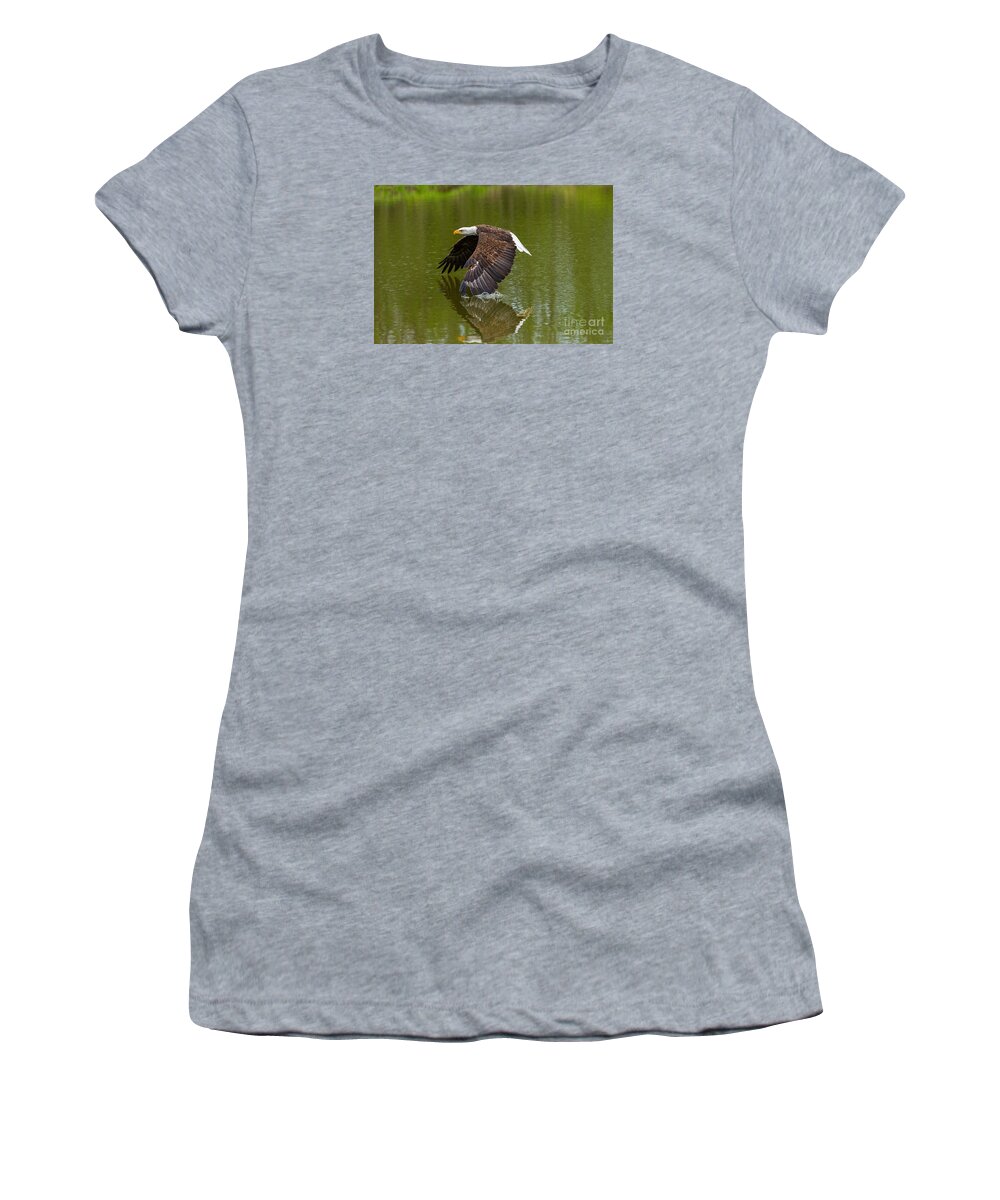 Birds Women's T-Shirt featuring the photograph Bald Eagle in low flight over a lake by Les Palenik
