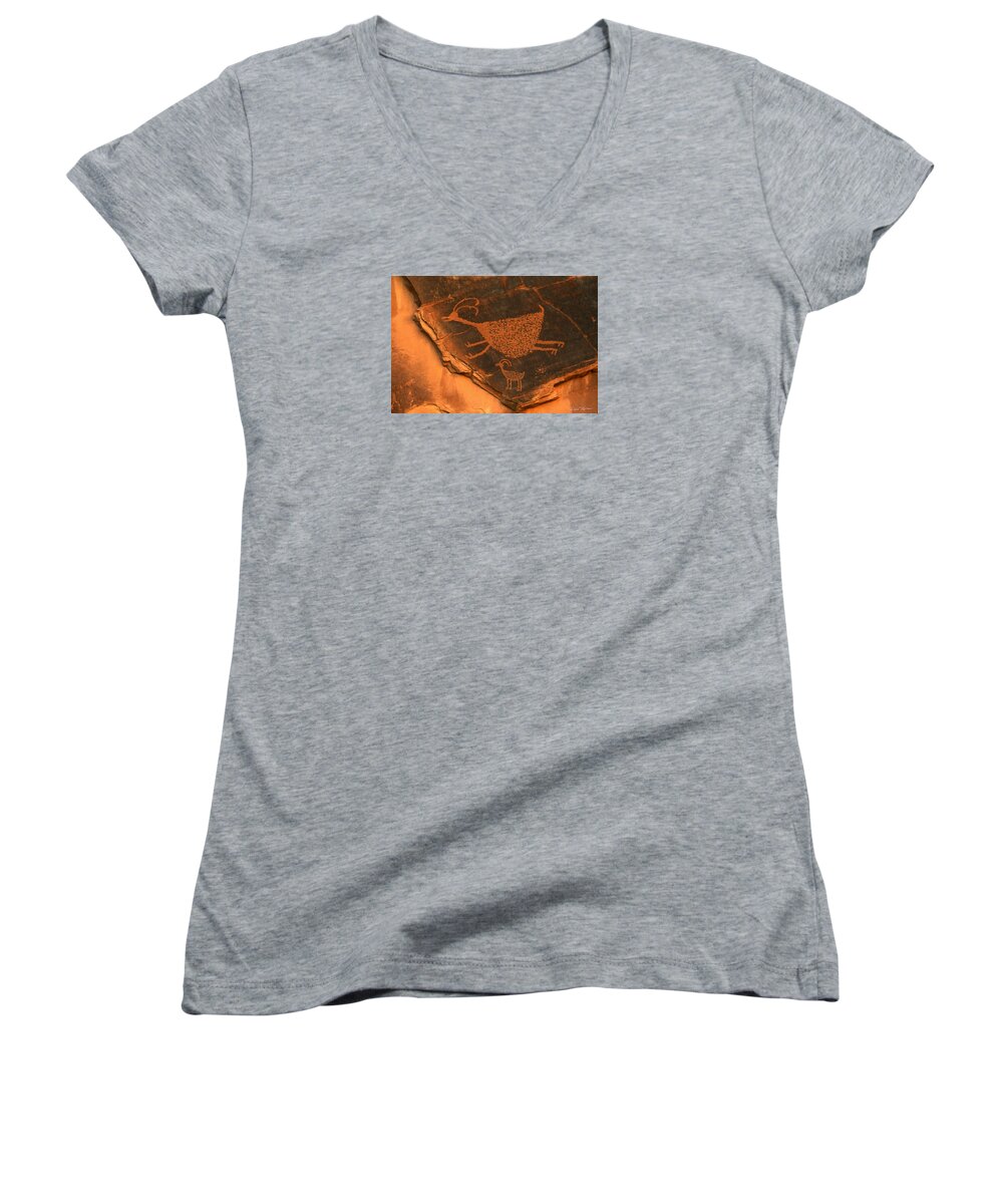 Petroglyph Women's V-Neck featuring the photograph Rock art at Eye Of The Sun Arch by Dan Norris