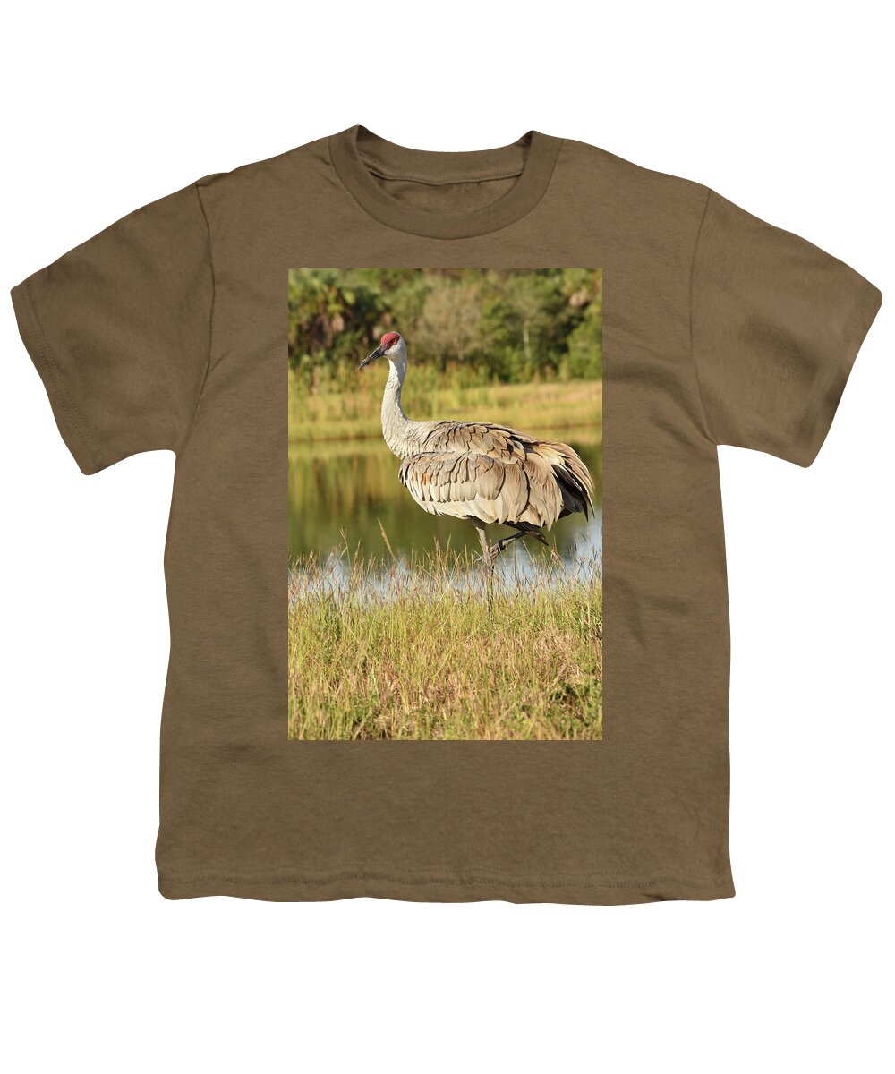 Crane Youth T-Shirt featuring the photograph Sandhill Crane Standing Beside a Lake by Artful Imagery