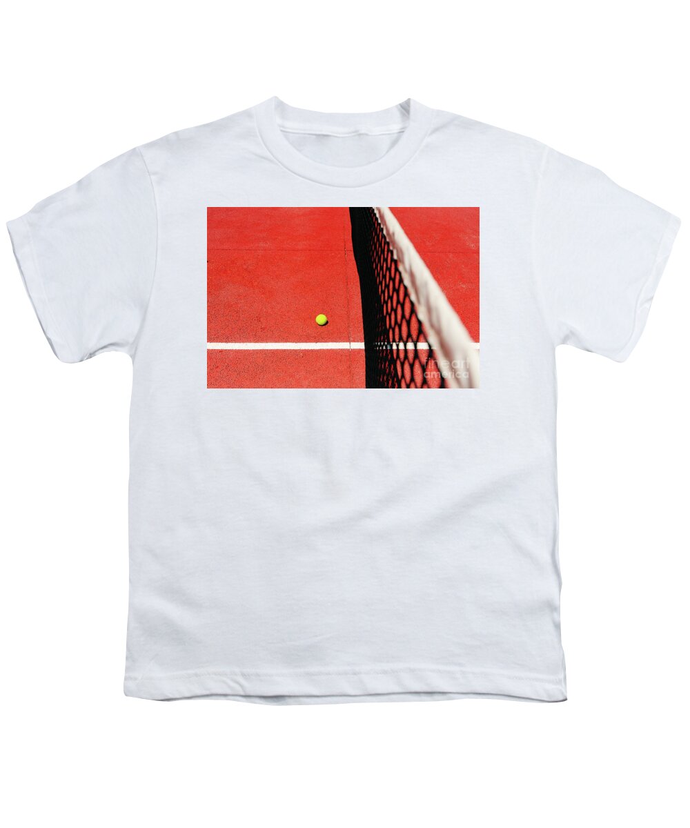 Ace Youth T-Shirt featuring the photograph A tennis ball on the textured floor of a red court near the net after losing a match point. by Joaquin Corbalan