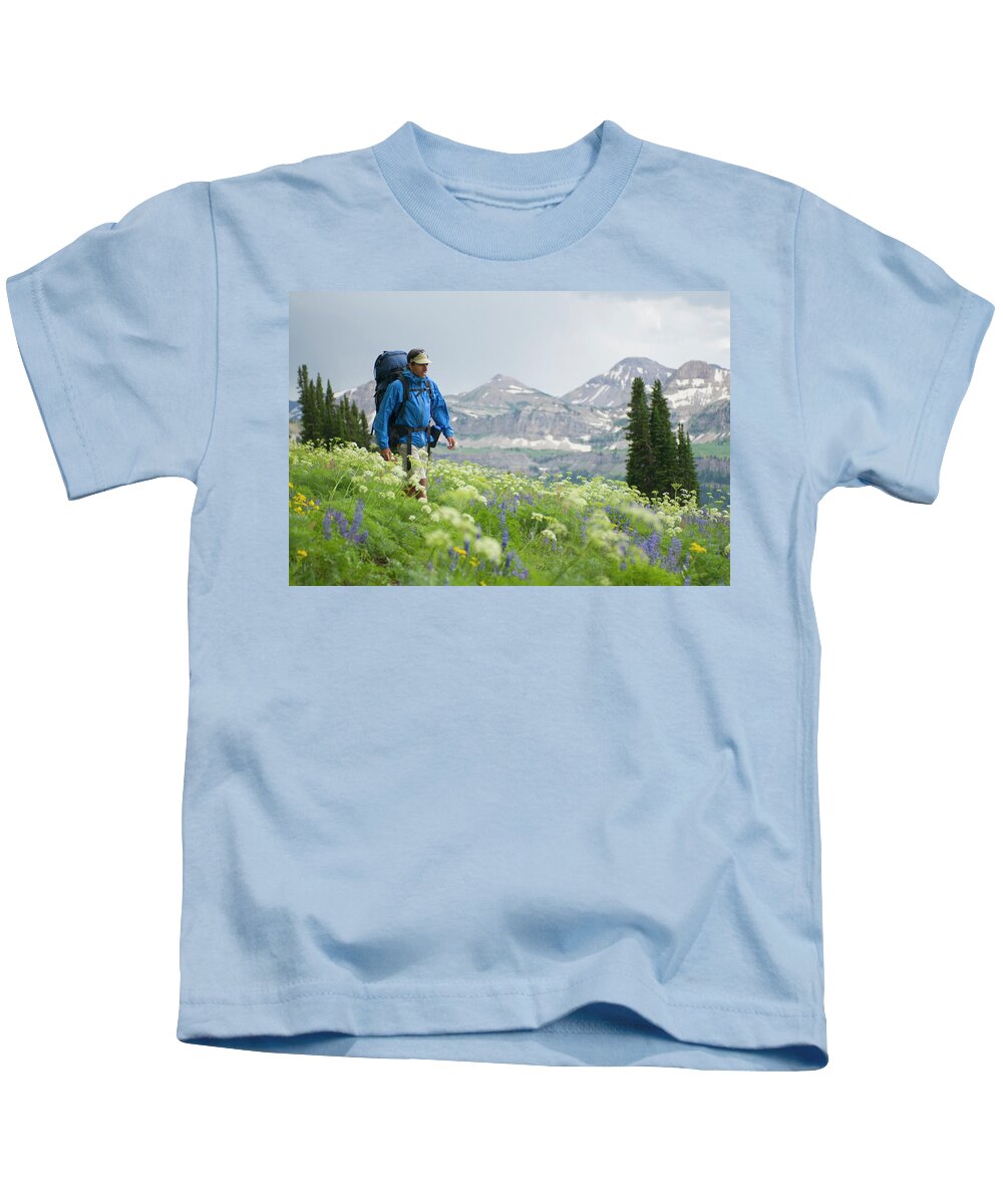 35-39 Years Kids T-Shirt featuring the photograph A Young Man Hikes Through A Flowery #1 by Jeff Diener