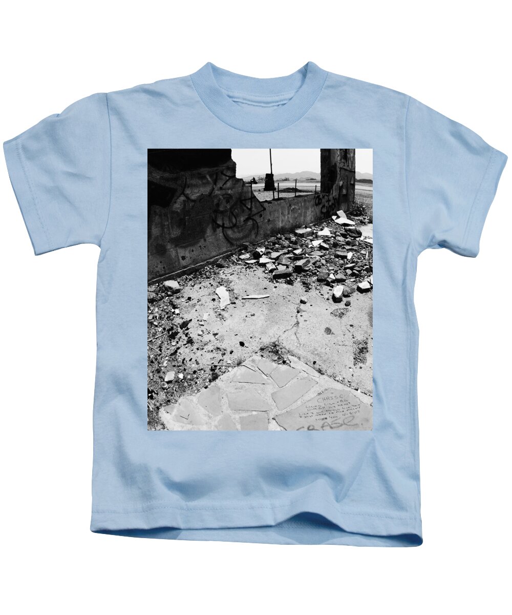 Left Behind In The Rubble Kids T-Shirt featuring the photograph Left Behind in the Rubble -- Motorcyclist and Graffiti in Amboy, California by Darin Volpe