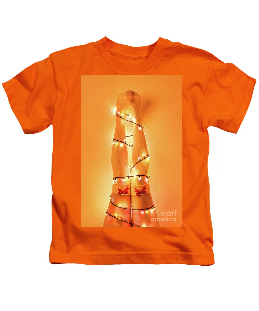 Christmas Kids T-Shirt featuring the photograph Female legs wrapped with christmas tree lights by Mendelex Photography