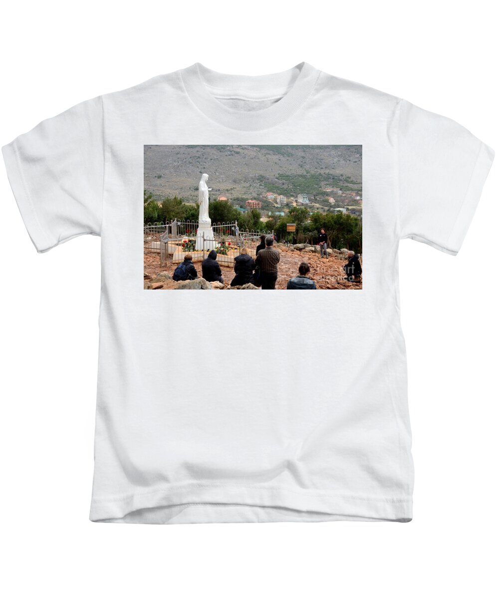 Virgin Mary Kids T-Shirt featuring the photograph Catholic pilgrim worshipers pray to Virgin Mary Medjugorje Bosnia Herzegovina by Imran Ahmed
