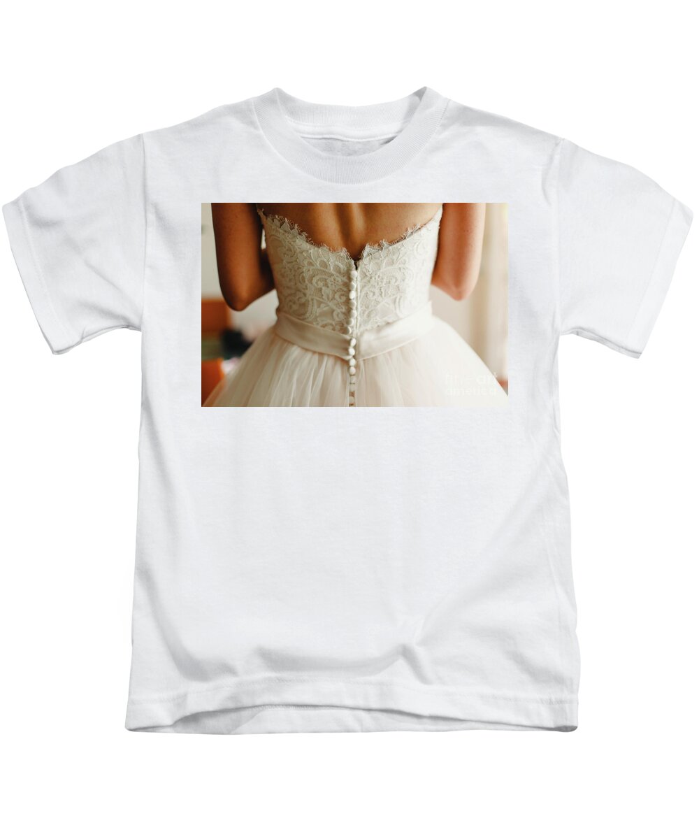 Back Kids T-Shirt featuring the photograph Bride getting ready, they help her by buttoning the buttons on the back of her dress. by Joaquin Corbalan