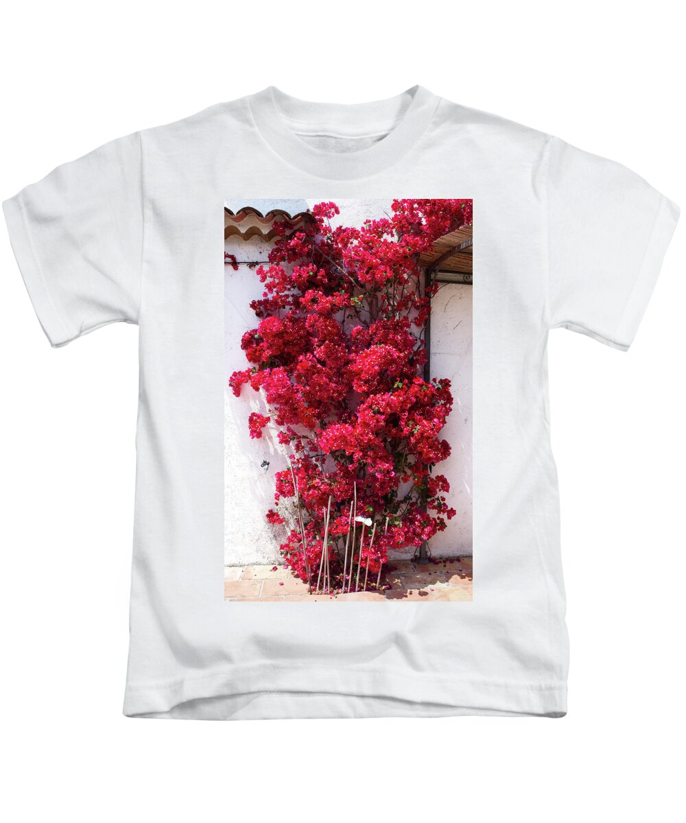 Background Kids T-Shirt featuring the photograph Glowing red bougainvillea in front of a white wall by Jean-Luc Farges