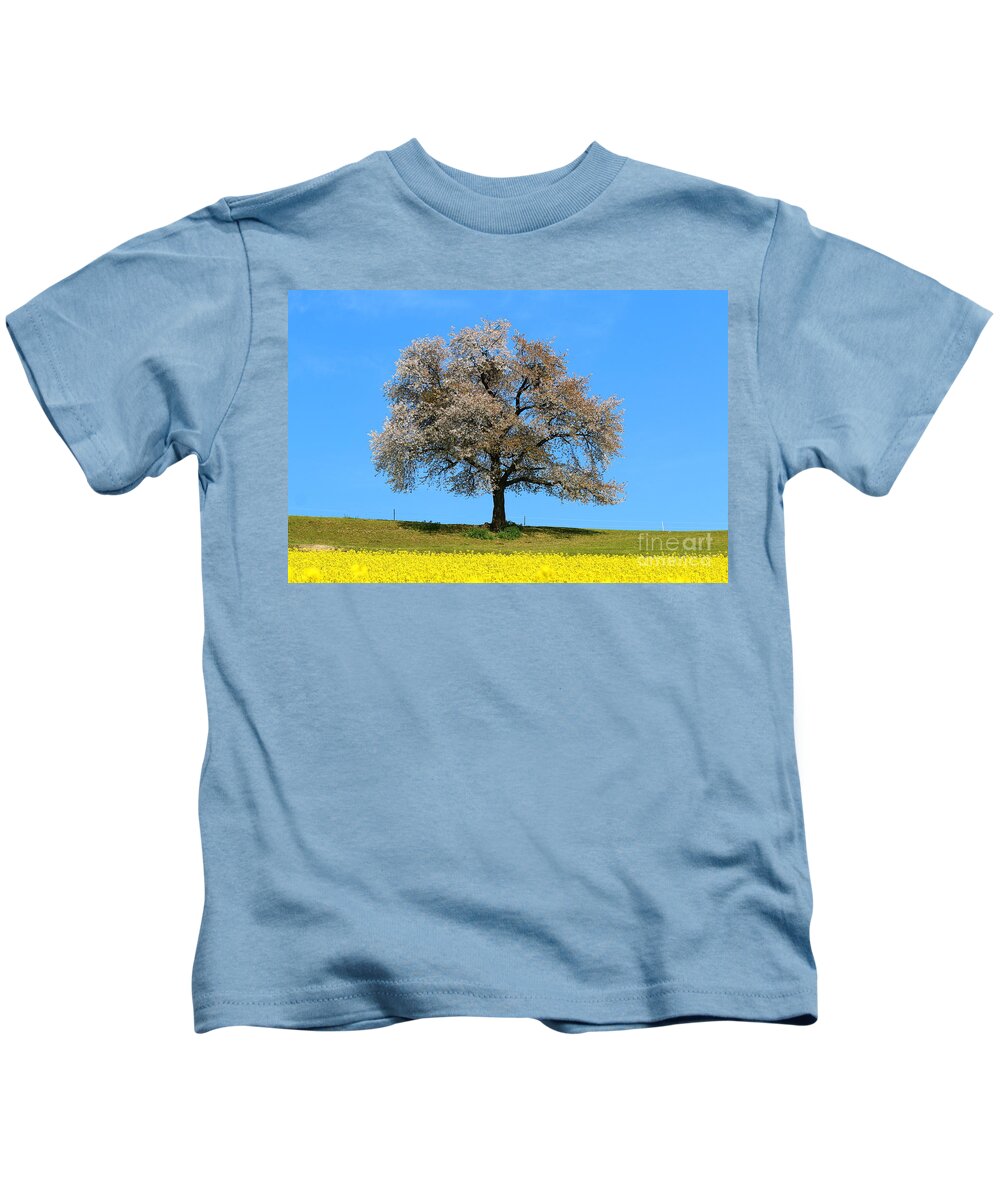  Agriculture Kids T-Shirt featuring the photograph A blooming lone Tree in Spring with canolas in front 2 by Amanda Mohler